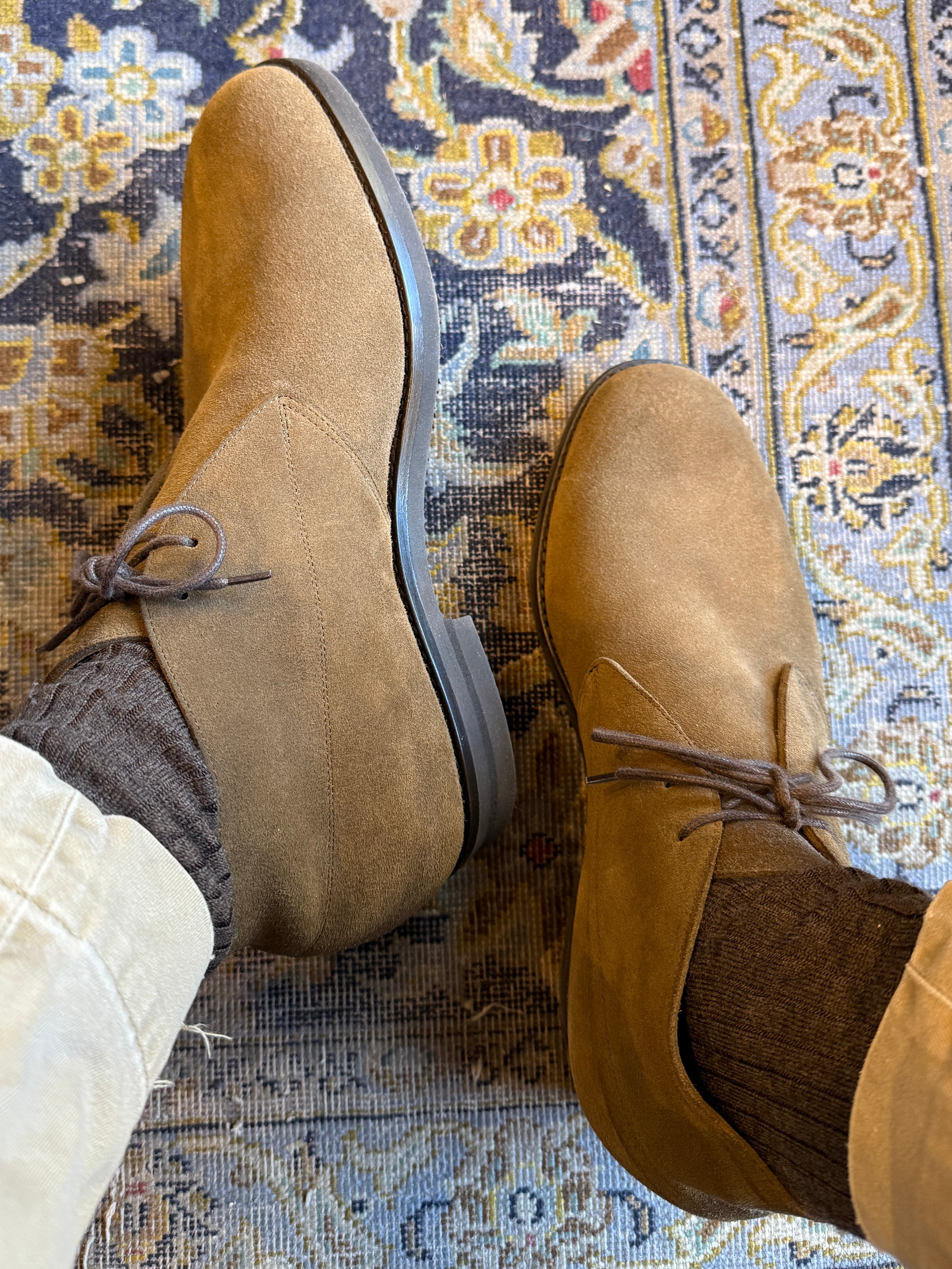 Brown suede shoes on a patterned rug