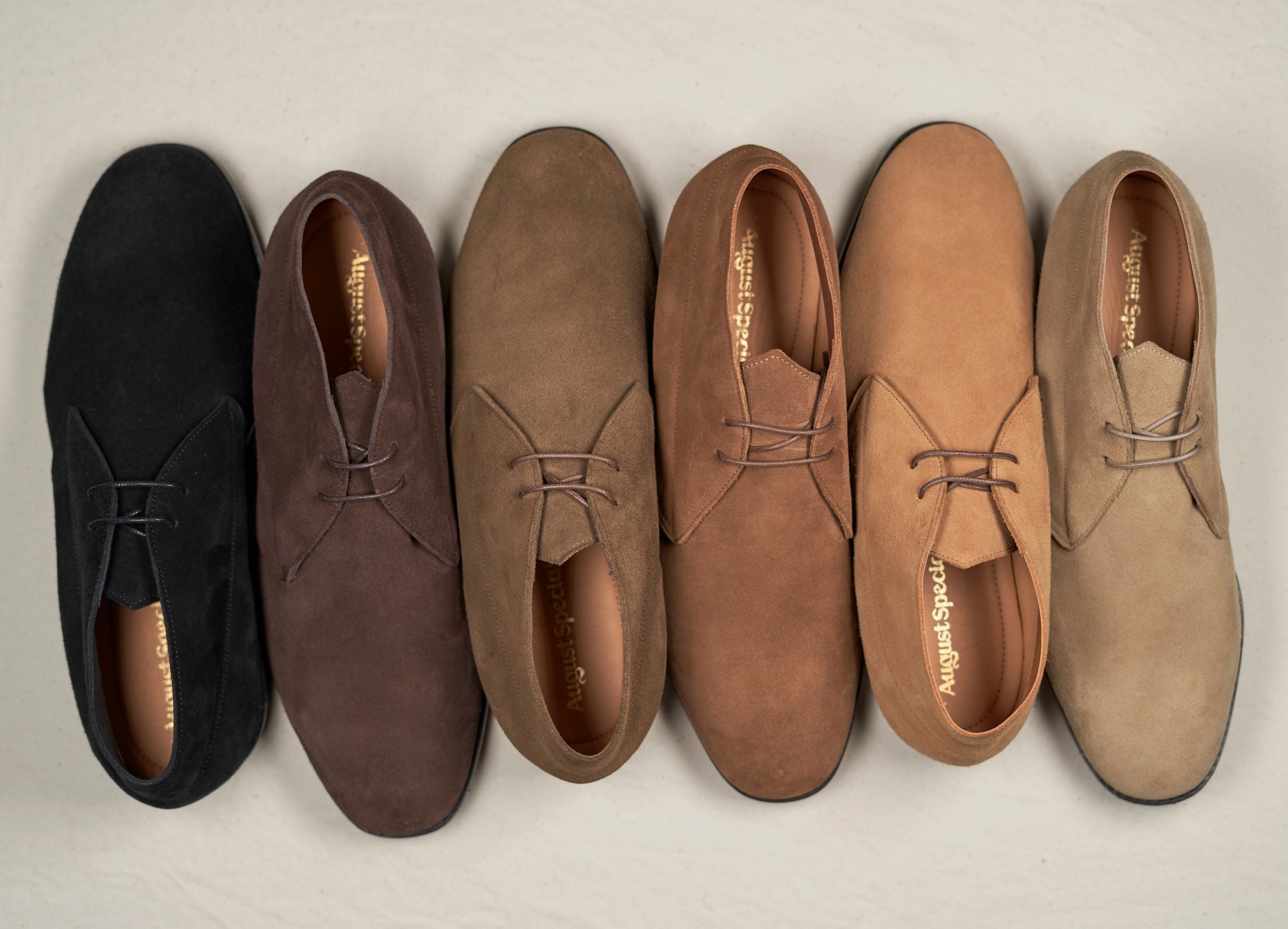 Set of six brown suede shoes arranged in a pyramid formation on a light gray background.