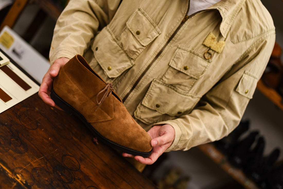 Man holding a brown suede chukka boot