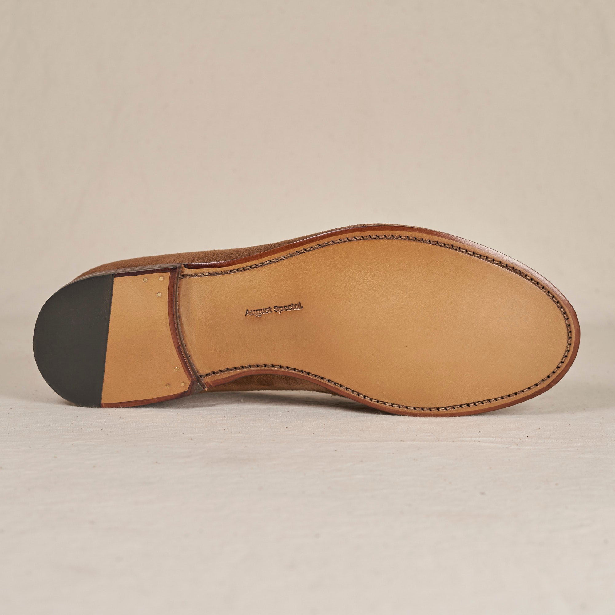 The outsole of a brown leather dress shoe, showing the tan leather footbed with 'Preston Park' embossed in the center and a black rubber heel cap, photographed on a light beige background.