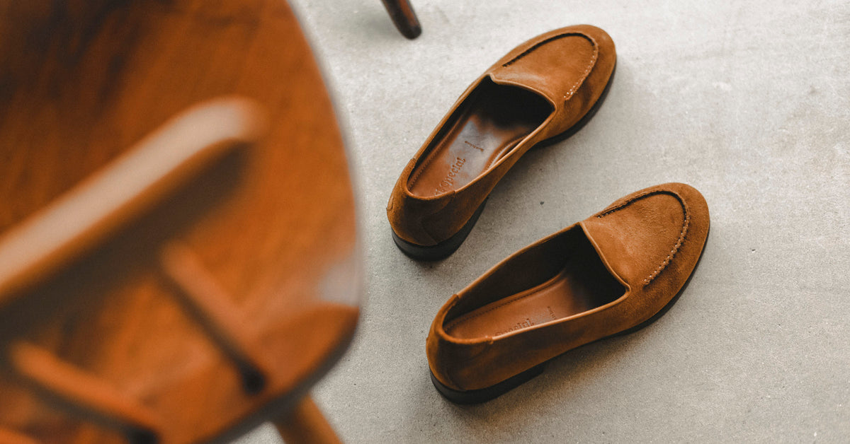 tan suede loafers sat on a concrete floor