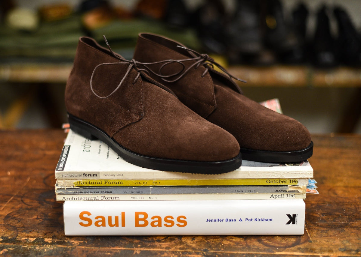 Brown suede chukka boot sat upon a pile of books