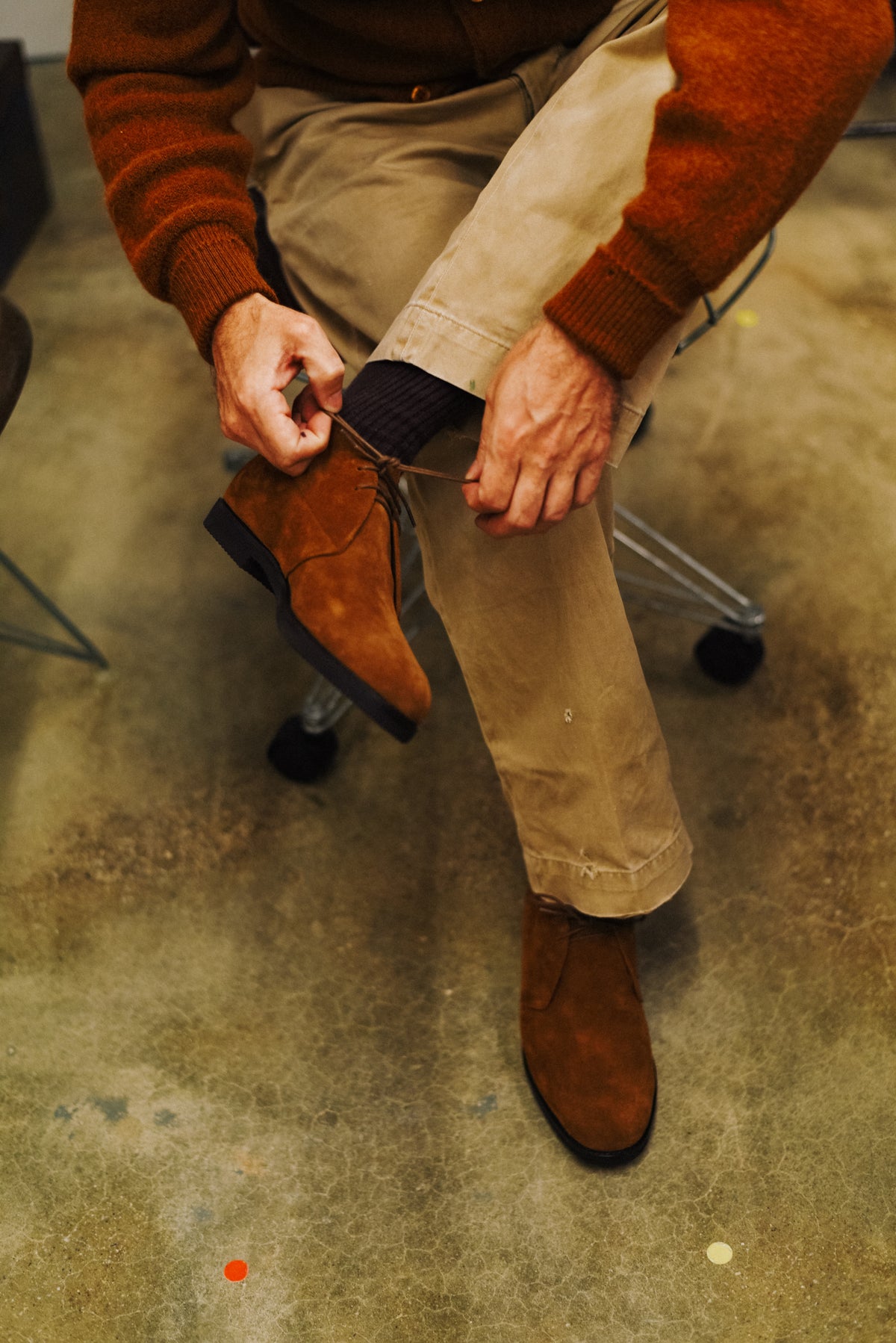 Seated man typing laces of brow suede boots