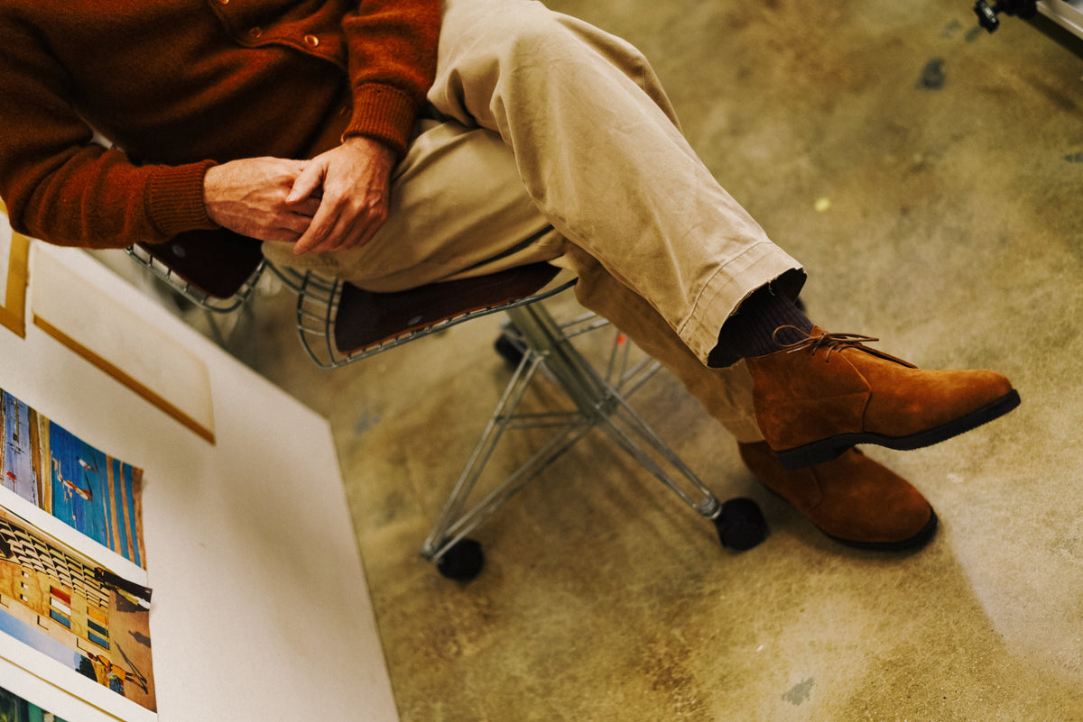 Man seated wearing chinos and brown suede shoes