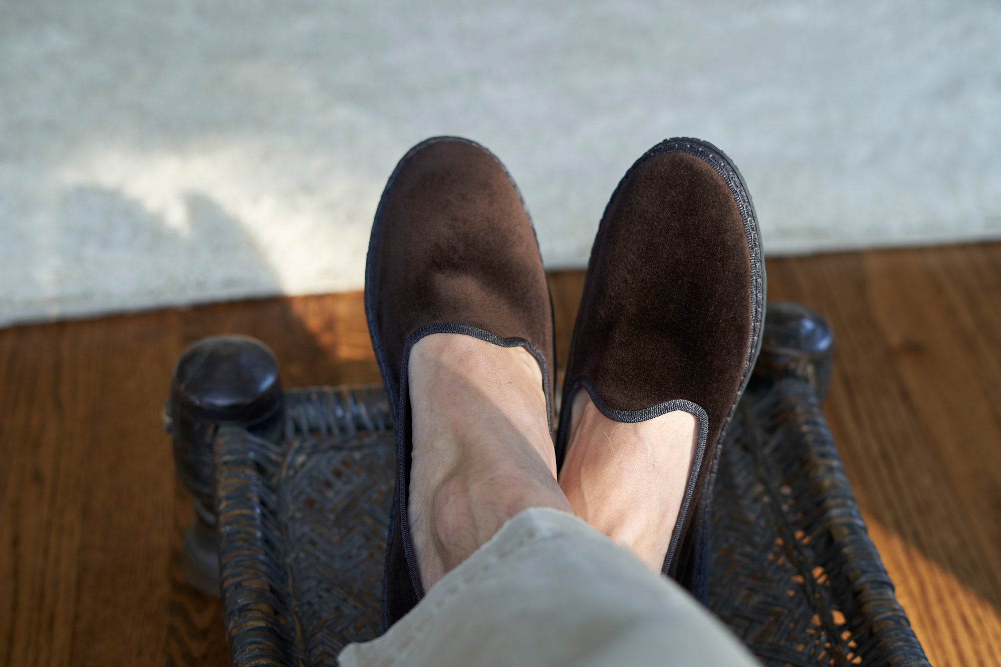 Brown suede shoes on a woven chair with a blurred background