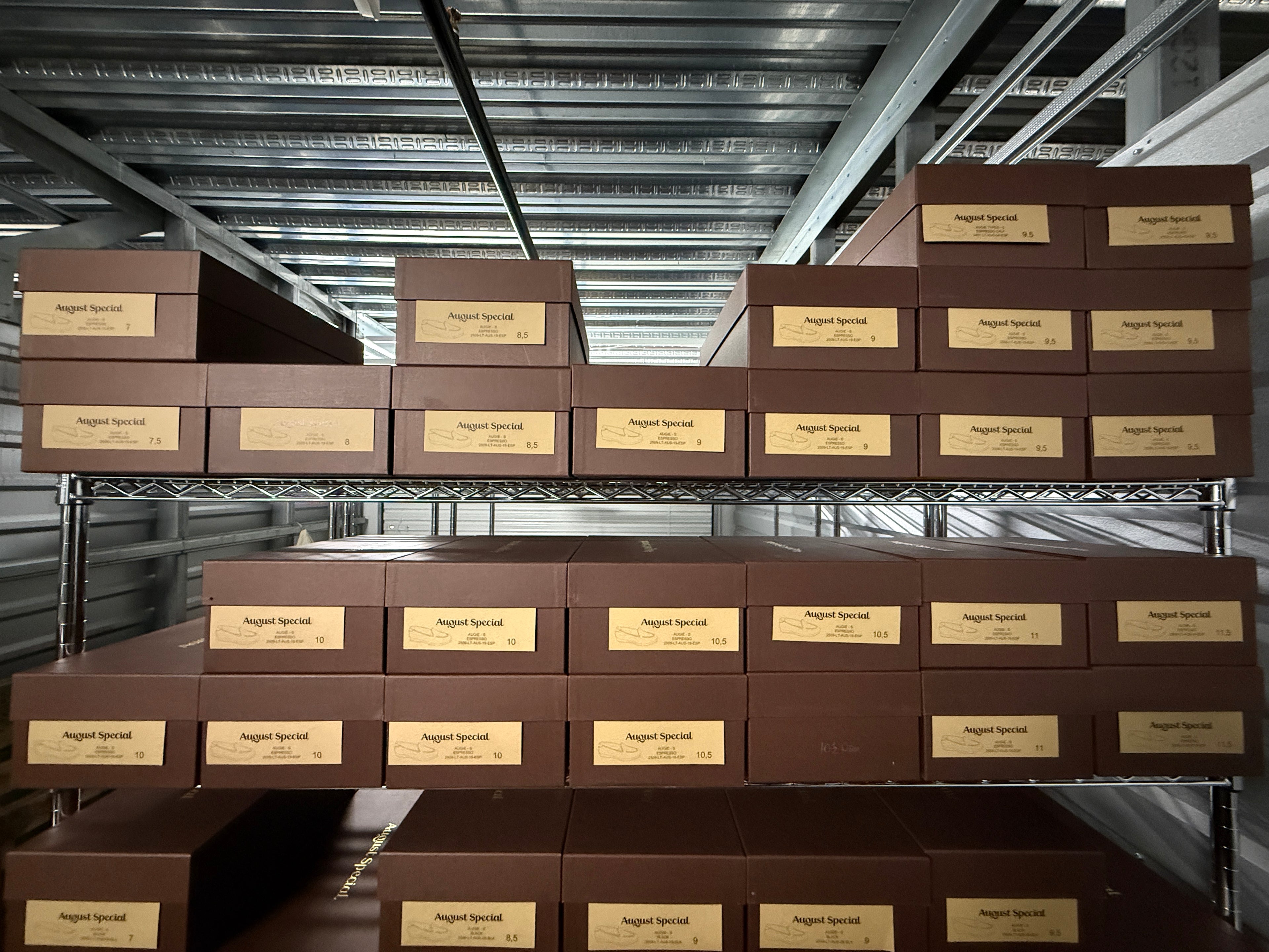 Stack of brown boxes with gold labels on metal shelves in a warehouse.
