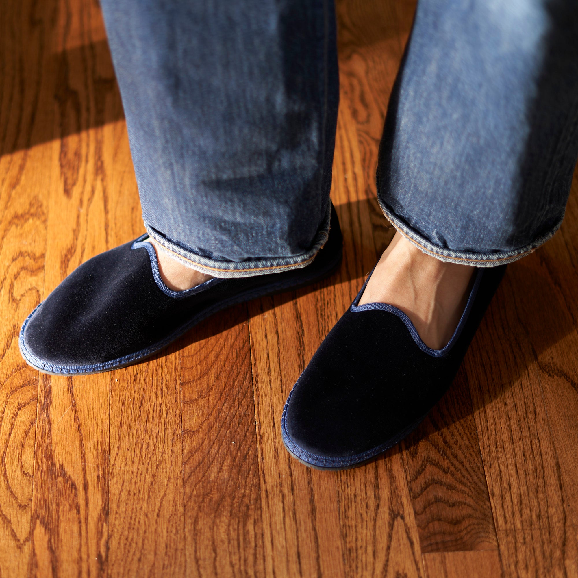 Person wearing navy slippers on a wooden floor