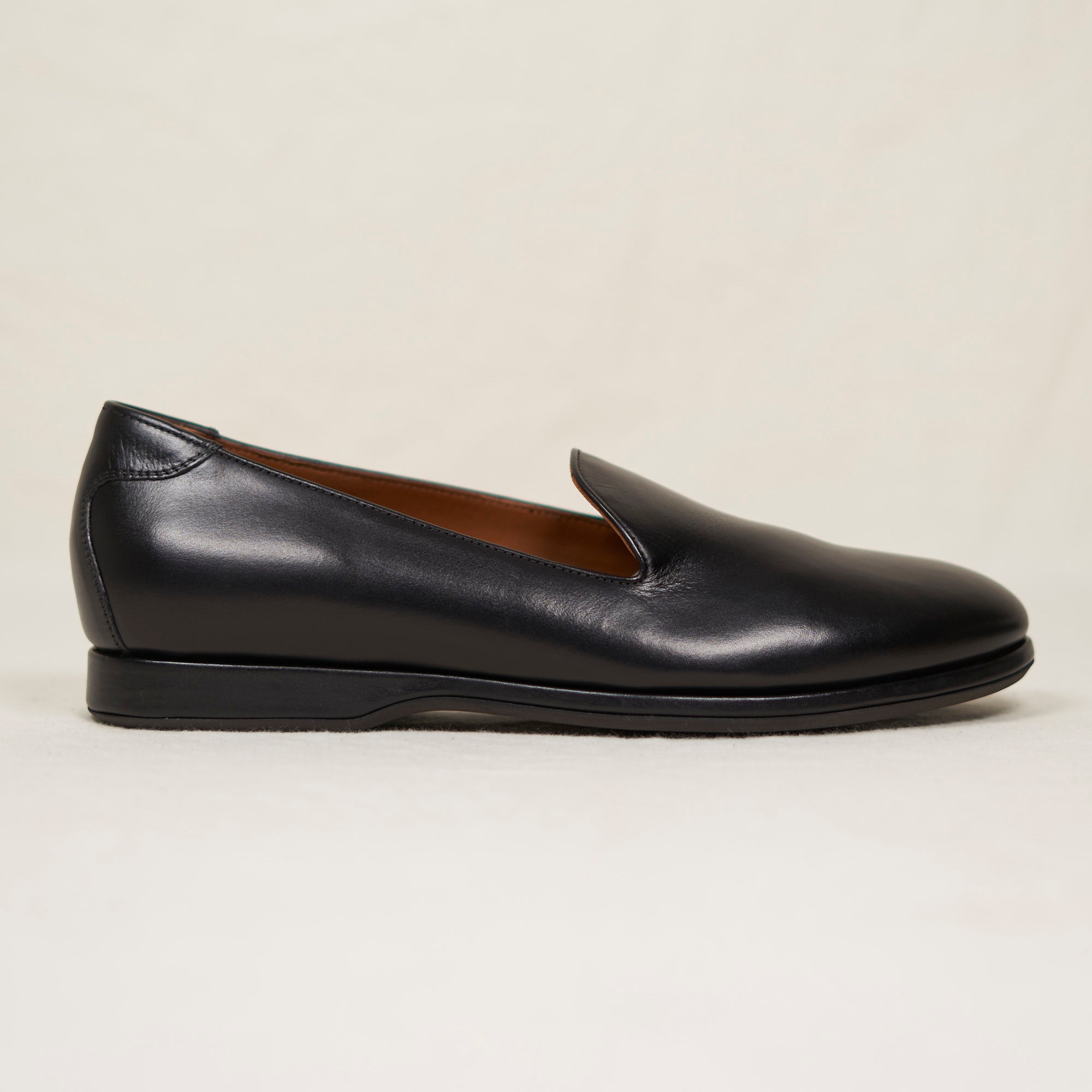 Black loafer shoe on a light beige background