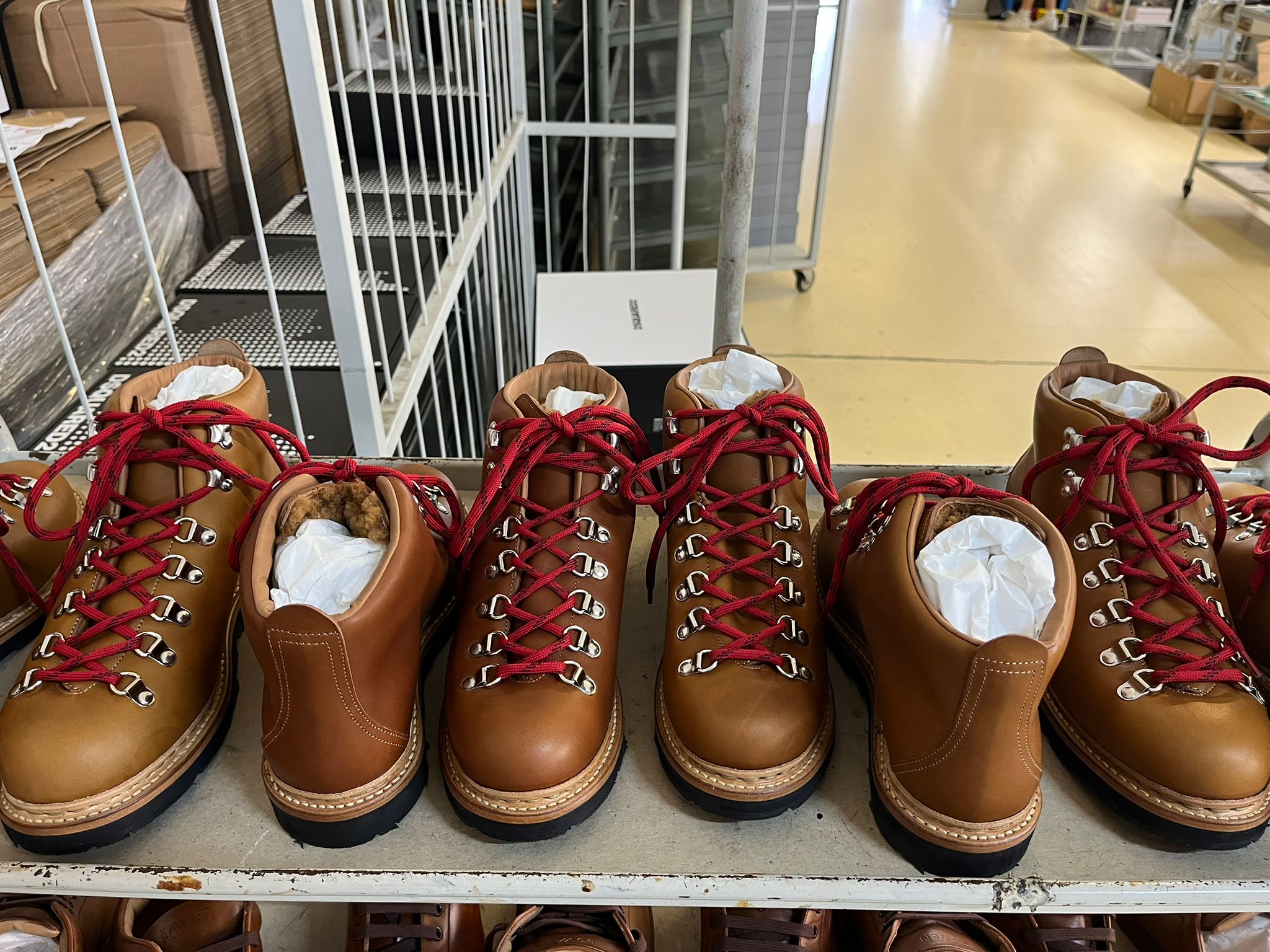 Brown hiking boots with red laces on a shelf in a store setting